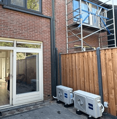 Buitenunits van airco's naast een bakstenen woning